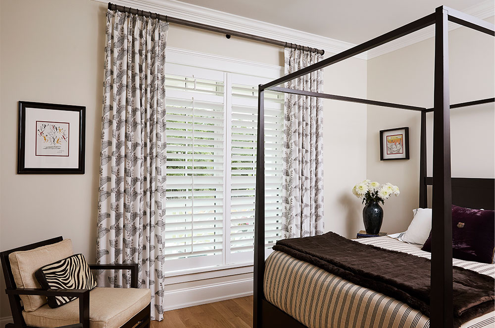 A bedroom with Olivia Pleat Drapery on Magnolia Sedona hardware.