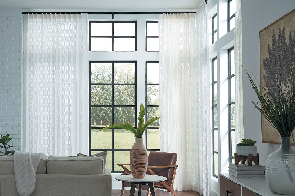 A sunroom featuring white sheer Single Pleat Drapery on Magnolia Custom Wrought Iron Hardware.