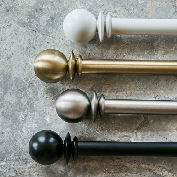 PowerView Motorized Drapery Hardware globe finials with rods in all four finishes on a grey marble background.