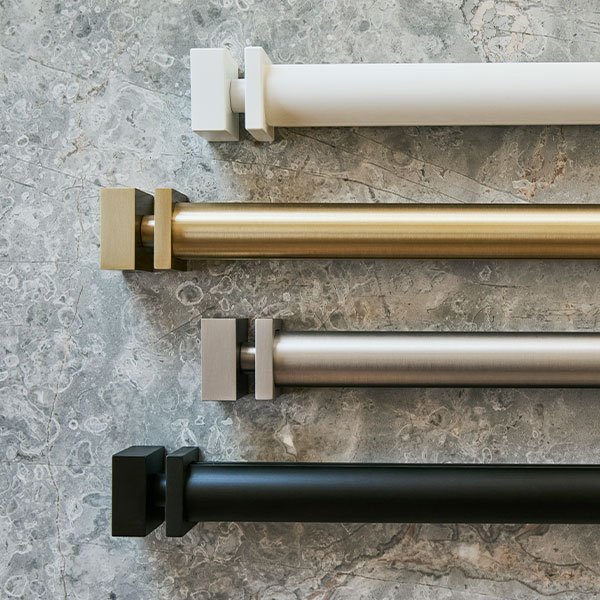 PowerView Motorized Drapery Hardware square finials with rods in all four finishes on a grey marble background.