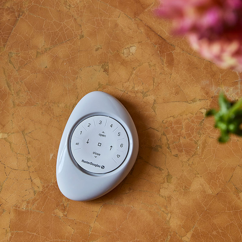 Top view of a PowerView Pebble Remote on a light brown marble table.