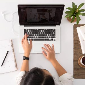 Top view of a woman at a desk working on a computer.