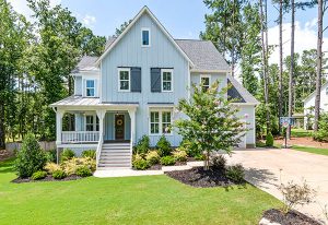 A light blue home on a sunny day surrounded by greenery.